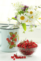 A bouquet of wildflowers and a glass bowl of red currant