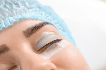 Young woman undergoing procedure of eyelashes lamination in beauty salon, closeup