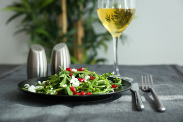 Plate with tasty arugula salad on table