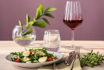 Plate with tasty arugula salad on table