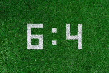 Football score.White numbers six and four are drawn on the green grass,creative scoreboard