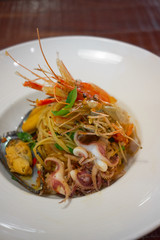 Spicy Seafood Spaghetti stir fried (Pad Cha) rolled in the fork on white dish of luxury restaurant