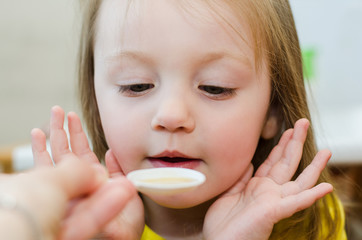 child takes medicine from a spoon