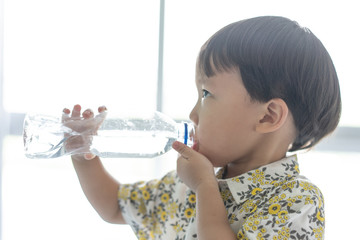 The boy is drinking a bottle of water.