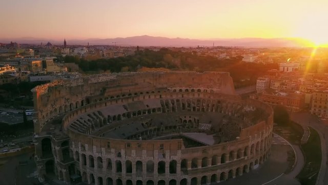 colosseum aerial view drone fly backwards at sunrise rome skyline italy