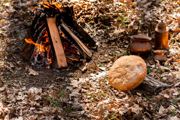 Home-made fresh bread on the background of fire in the autumn forest