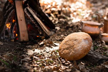Home-made fresh bread on the background of fire in the autumn forest