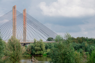 orange suspension, wire bridge Zaltbommel, called Martinus Nijhoff brug, The Netherlands. with trees and ditch