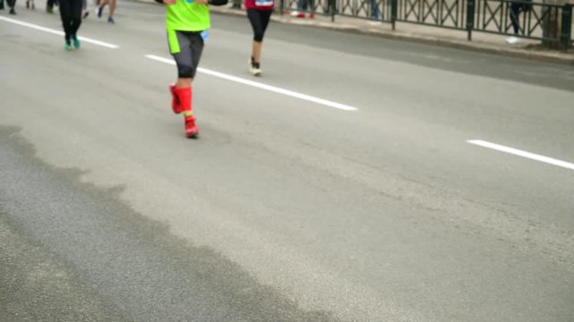 blurred view of people feet running on asphalt road at city marathon