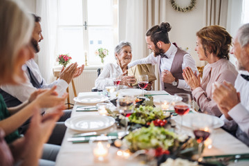An elderly grandmother in a wheelchair celebrating birthday with family, party concept.