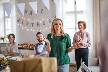 Happy young woman receiving a gift on indoor party.