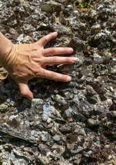 Hand on the stone rock in the mountains as background