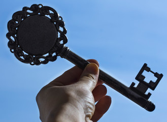 old big key in a man's hand against the sky