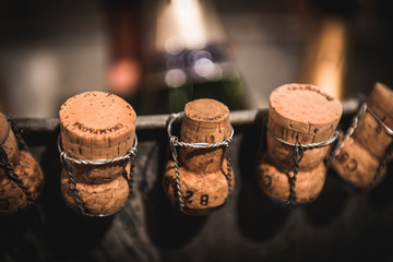 Unchained champagne corks in series with blurred wine bottles on the background