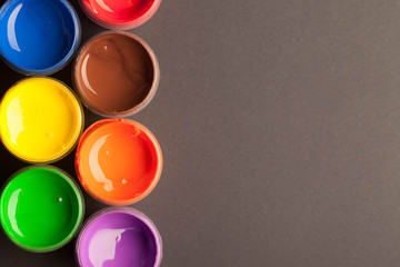 Jars with different colors of acrylic paint on a black background