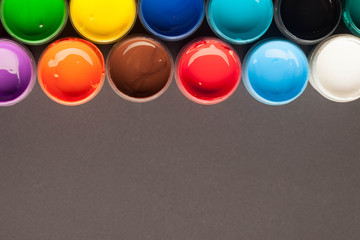 Jars with different colors of acrylic paint on a black background