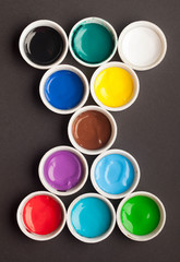 Jars with different colors of acrylic paint on a black background