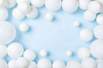 Pastel blue table with white balloons top view. Party or birthday background. Flat lay.