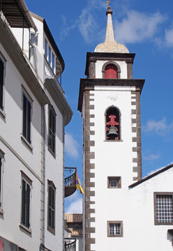 a street of old white painted houses and the tower of the historic parish church of saint peters in funchal madeira