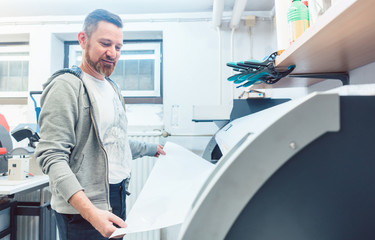 Man working on large format printer in advertising material agency