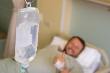 Close-up. Male hand with a dropper during chemotherapy in a hospital. The man is in the hospital room, without focus. Health is a topic of health and healing.