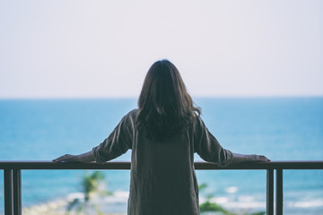 A beautiful asian woman standing and enjoy watching the sea view at balcony