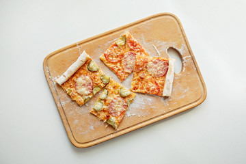 Pizza with mozzarella cheese, salami, tomatoes and spices. Italian pizza on a wooden board. Close-up