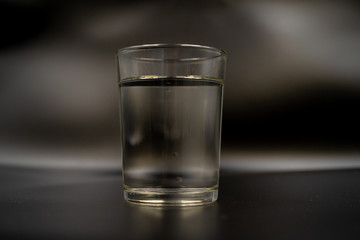 Just a glass of water on a dark wooden table. Mineral water in a glass on a black background. A...