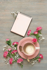 Cup of creamy coffee, notepad and flowers