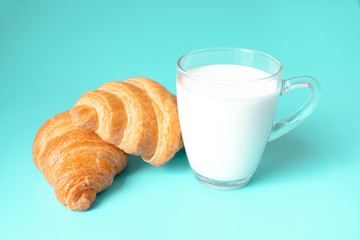 Croissants and milk on color background.