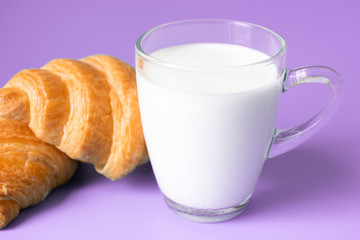 Croissants and milk on color background.