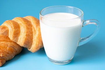 Croissants and milk on color background.