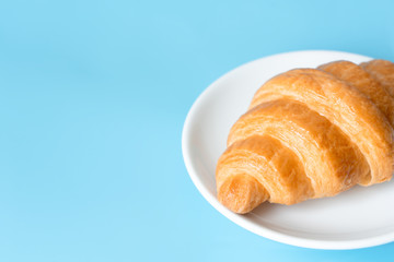 Croissant in a white plate on color background