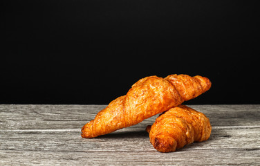Croissant. fresh and tasty croissants on wooden table, black background, space for text