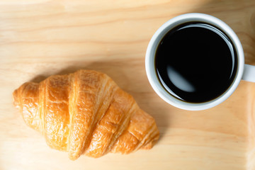 Croissants and coffee on wooden background.