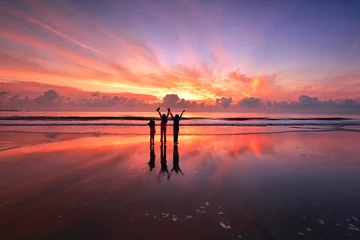  Silhouet van kinderen die over het strand staan met prachtige zonsondergangreflecties © fiz_zero