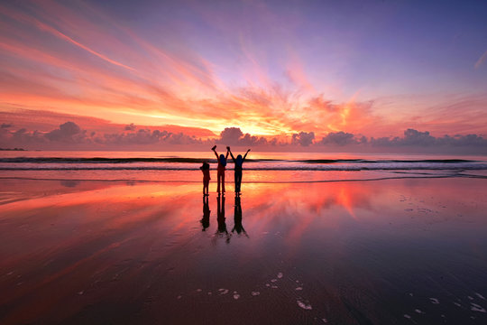 Silhouette Of Kids Standing Over The Beach With Beautiful Sunset Reflections