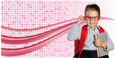 Cute little schoolgirl in glasses on library background