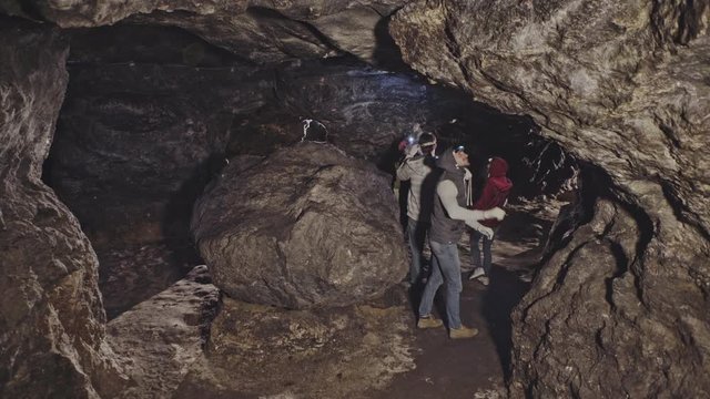A group of tourists are traveling in an underground cave with flashlights on helmets