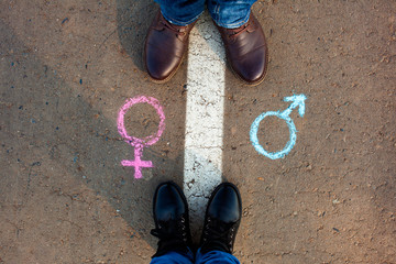 Gender symbols or signs for male and female drawn on asphalt. Male and female legs.