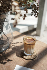 Iced coffee latte with brown upper layer coffee and white lower layer fresh milk in glass on wooden table