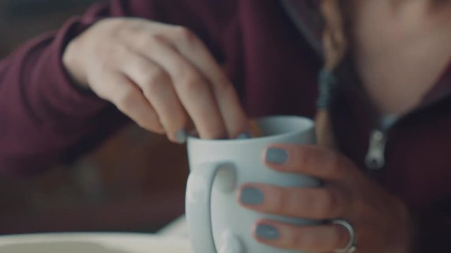 Close up shot of a women dipping a rusk in a cup of coffee.