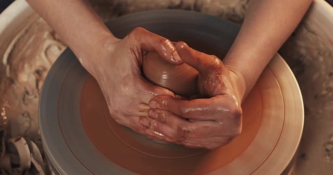 Potter makes pottery from clay close up. Making ceramic products from red clay. Twisted potter's wheel. Man hands making clay jug. Handmade, craft.