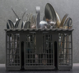 cutlery in the dishwasher basket on gray background