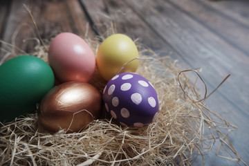Fototapeta na wymiar Close up colorful Easter eggs in nest on wooden table.
