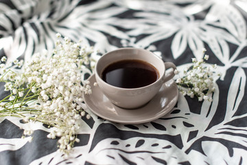 Cup of coffee and candle on rustic wooden serving tray in the cozy bed with blanket. Knitting warm woolen sweater in the autumn weekend, top view.
