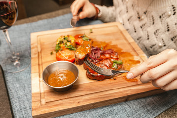Woman hand holding fork with grilled beef steak in restaurant