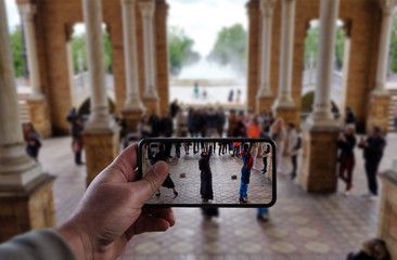 Man hand take a photo with smart phone to traditional spanish street falmenco dancer in the Square of Spain (Plaza de Espana) Seville.