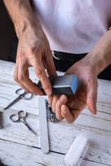 Man doing his nails at home. Hands close-up. Polishing his nails.