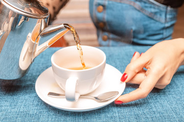 A woman pours tea from a kettle in a restaurant